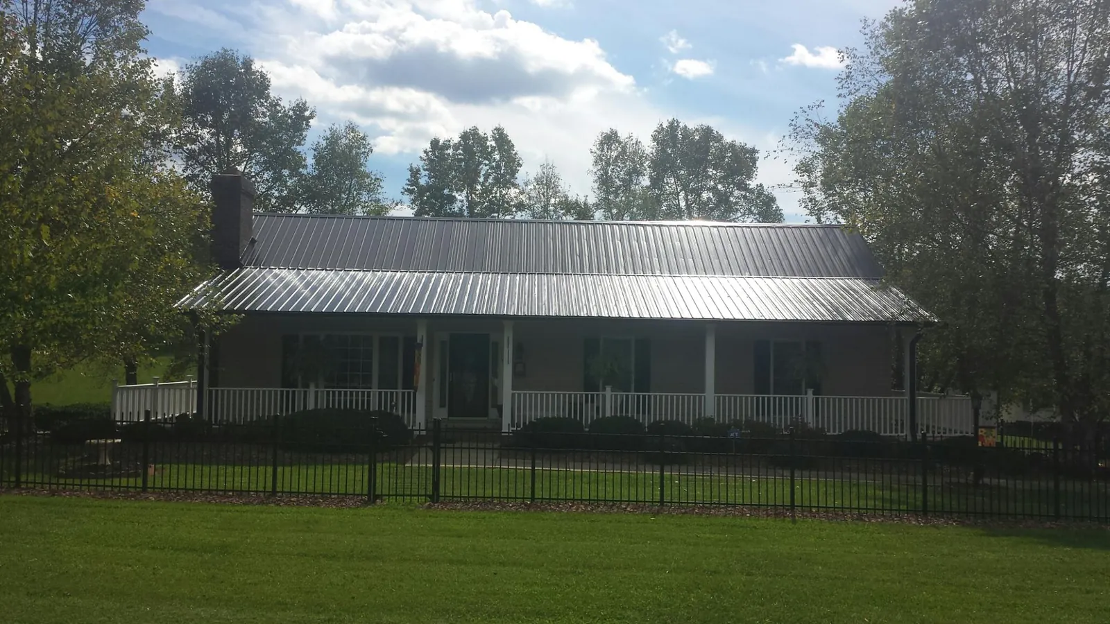 Gray metal roof on a brick ranch with a full width front porch — Gutter Guard Installation work by our crew in Daleville